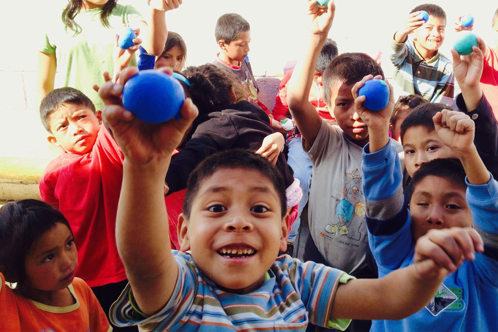 Happy children holding up blue balls